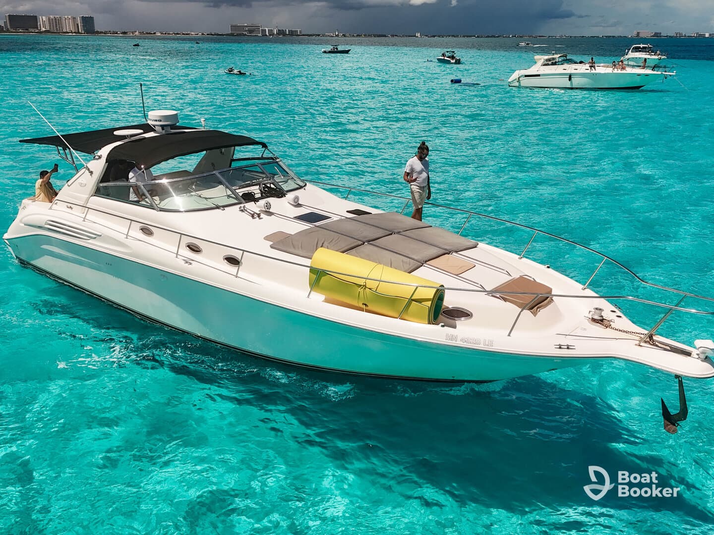 A sleek yacht navigates through stunning turquoise waters, showcasing a perfect day on the water with guests enjoying the scenery.