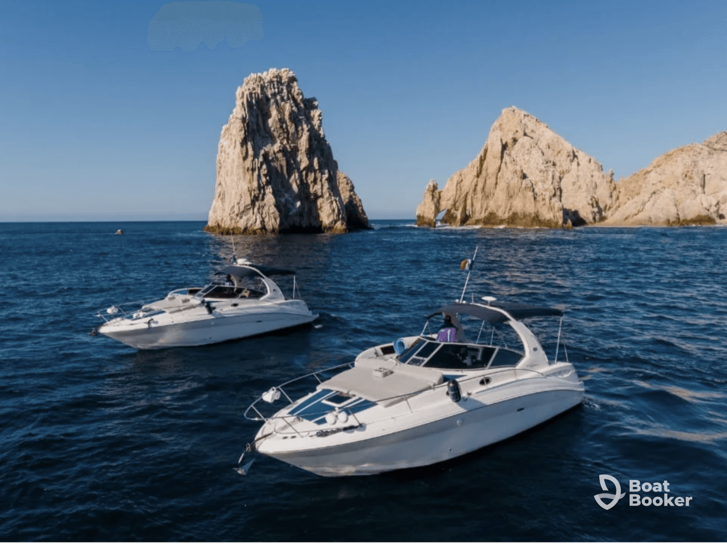 A stunning aerial view of two yachts cruising near dramatic rock formations, showcasing the beauty of the coastline and perfect for luxury boating experiences.
