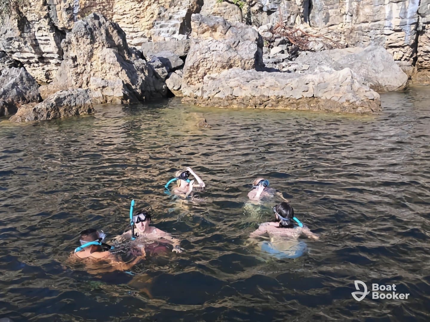 A group of snorkelers explores the clear waters near a rocky coastline, enjoying an adventurous day in nature.