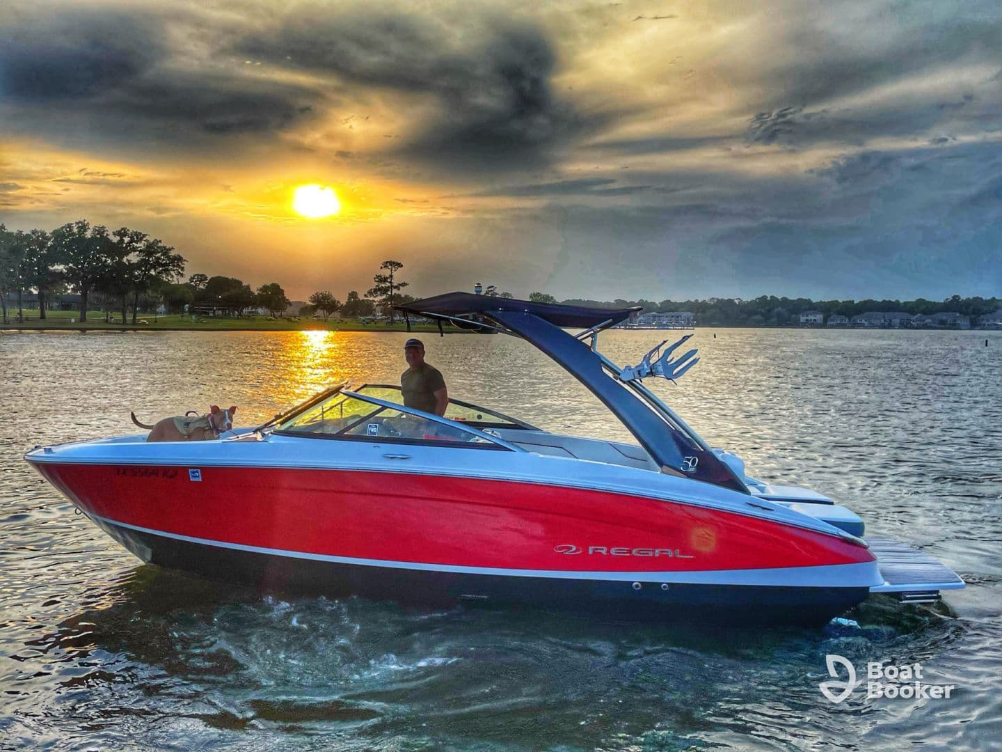 A man enjoys a sunset cruise on a Regal boat with his dog, capturing a serene moment on the water as the sun sets in the background.