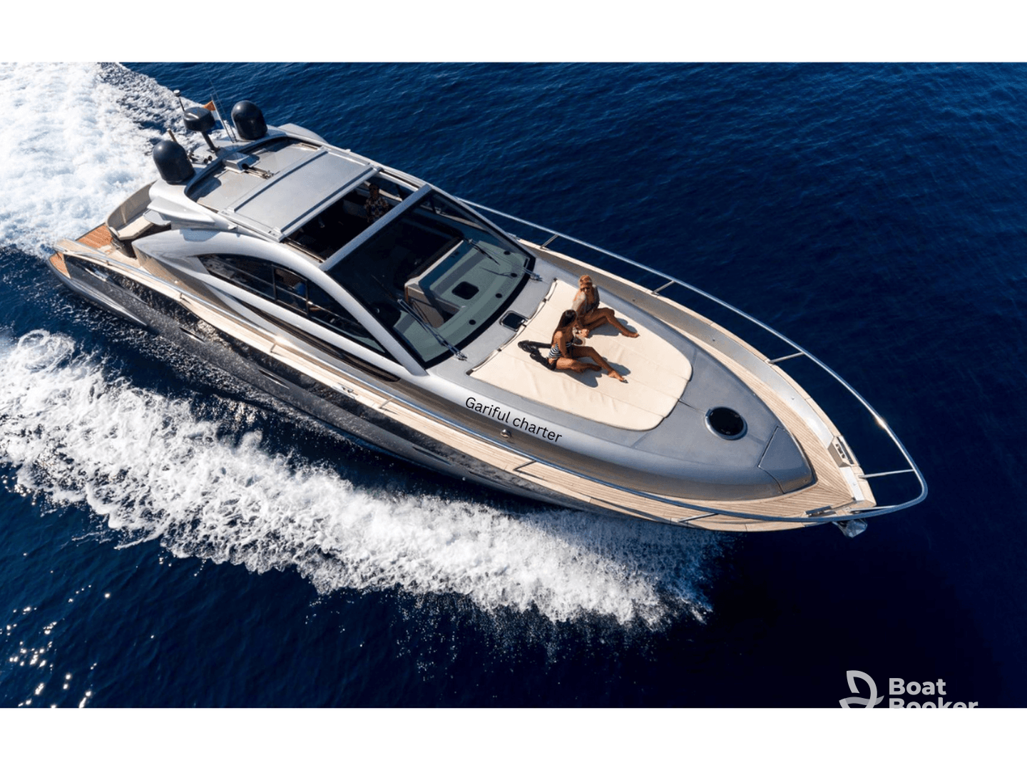 An aerial view of a luxurious yacht cruising through deep blue waters, with two guests relaxing on the deck — perfect for sun-soaked adventures and memorable outings.