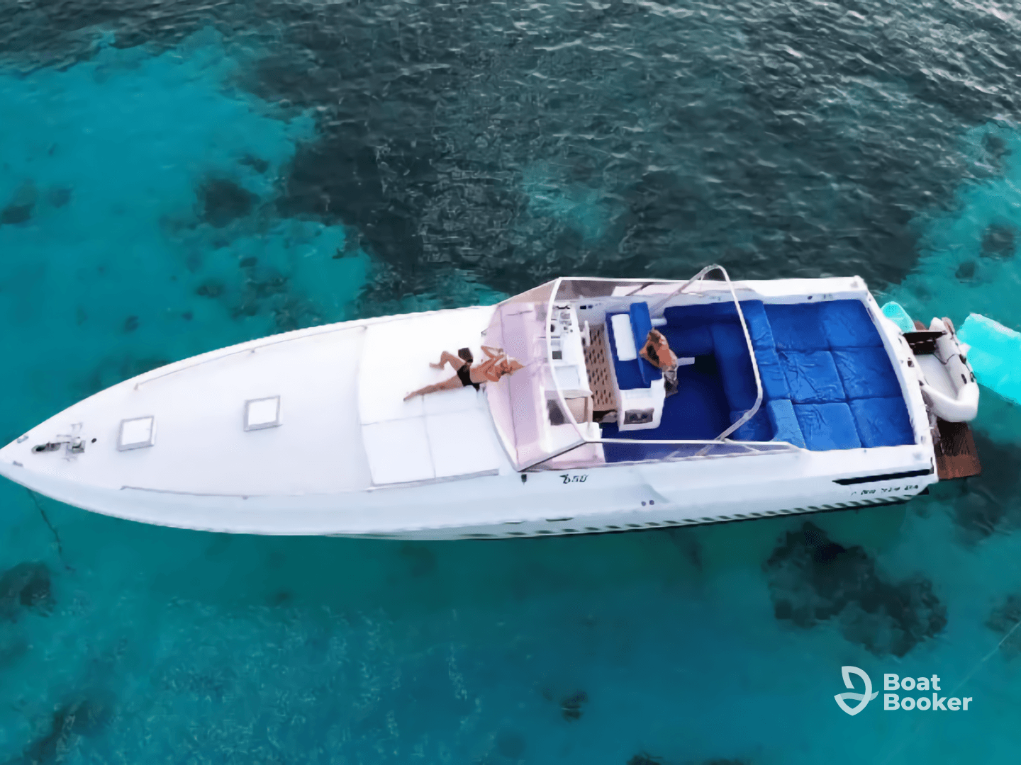 An aerial view of a couple relaxing on a boat surrounded by stunning turquoise waters, perfect for a day of leisure and exploration on the sea.