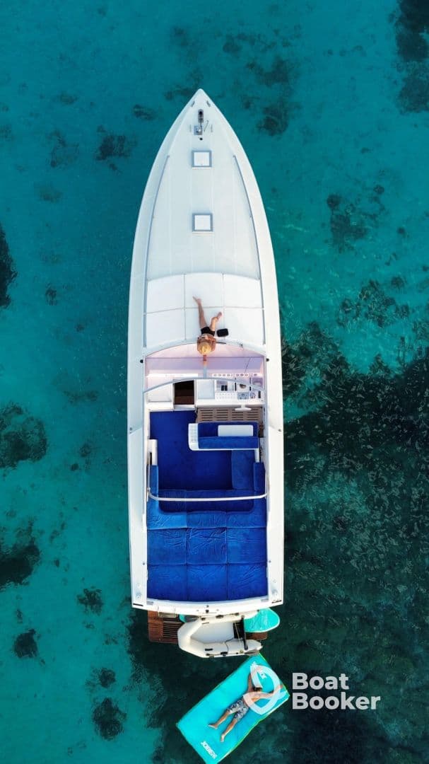 An aerial view of a relaxing day on the water, featuring a person lounging on a boat and enjoying the turquoise sea — perfect for summer getaways and leisure activities.