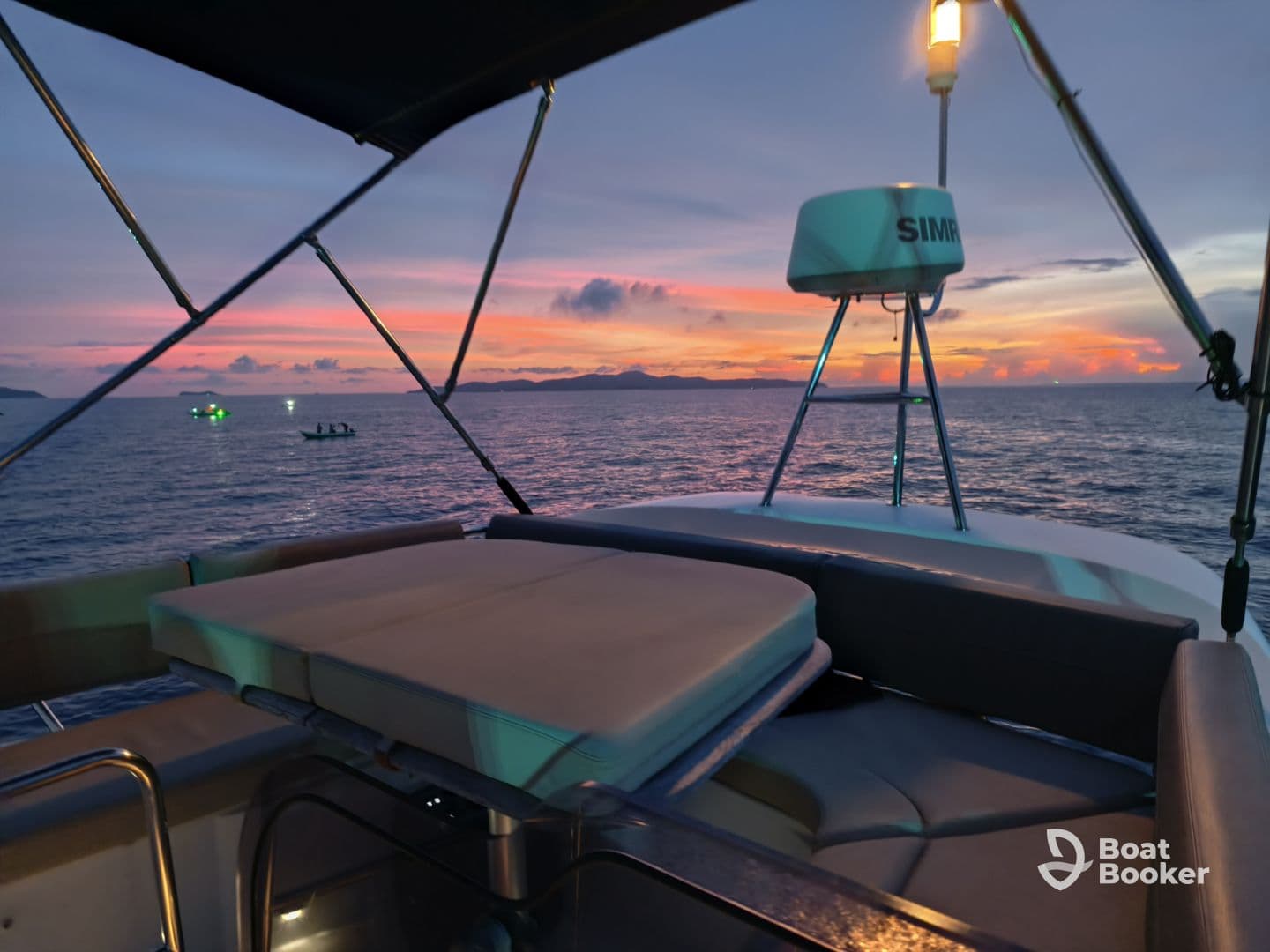 A serene sunset view from the deck of a boat, showcasing the tranquil waters and distant boats — perfect for evening cruises.