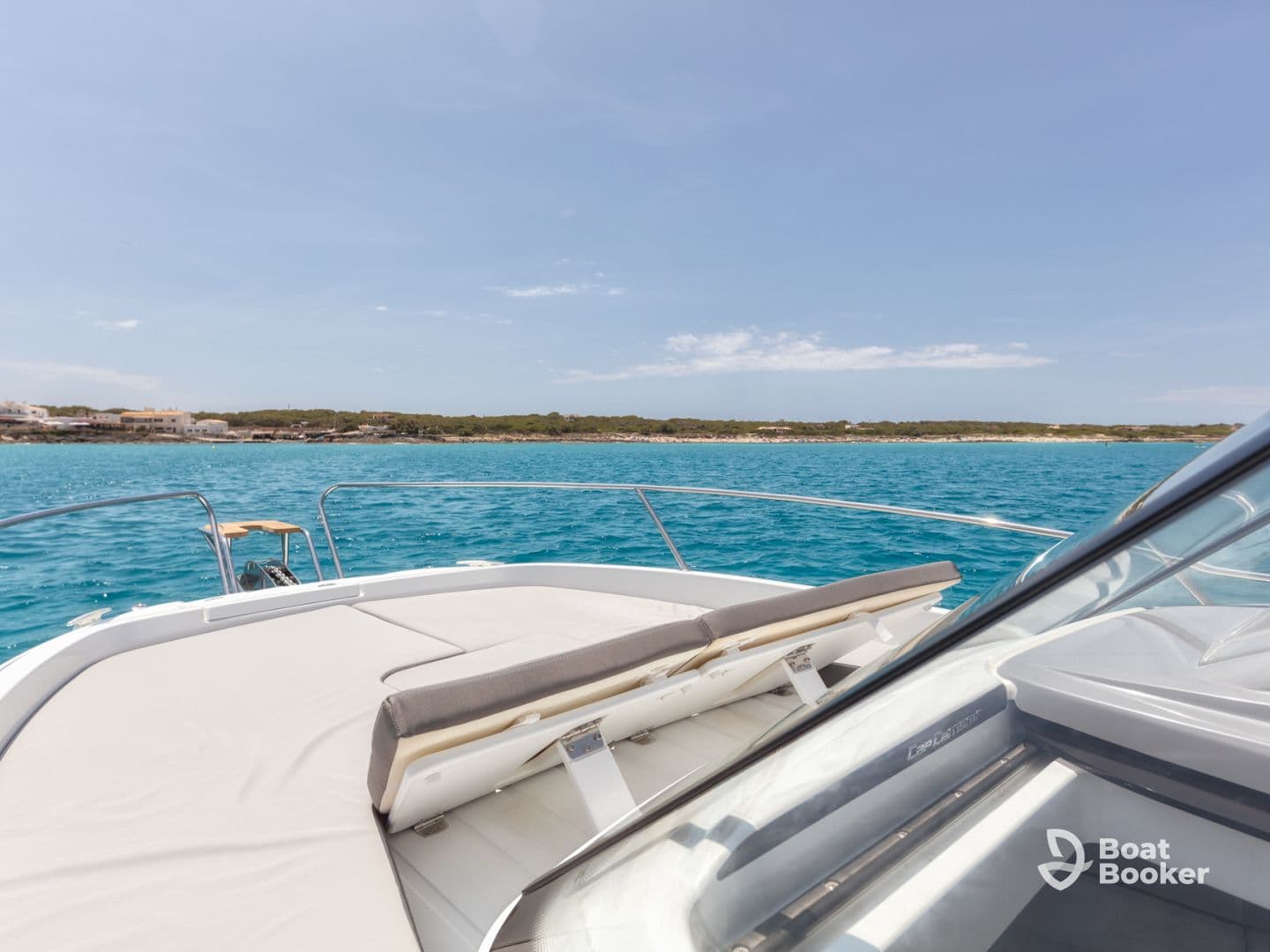 A serene view from the bow of a yacht, showcasing the beautiful turquoise waters and a glimpse of the coastline — perfect for a relaxing day on the water.