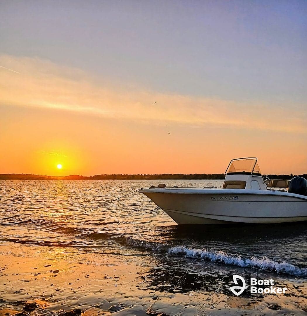 A serene sunset view featuring a speedboat anchored at the shore, perfect for evening cruises and relaxation on the water.