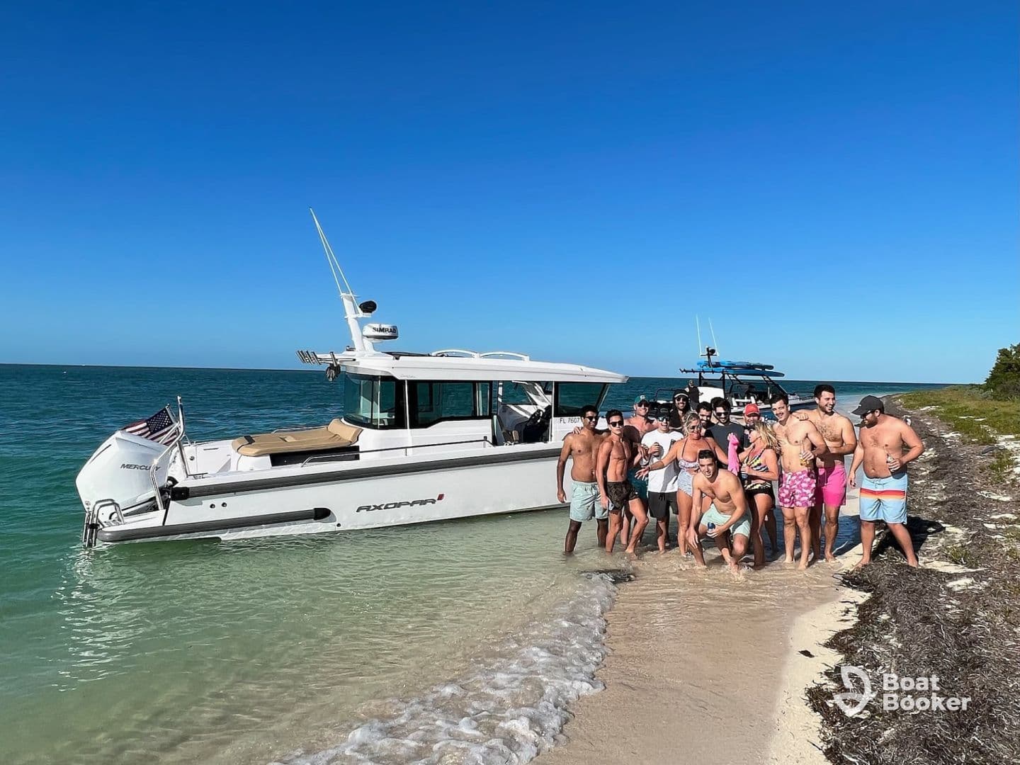 A lively group of friends gathers on the beach next to a stylish boat, enjoying a fun day in the sun — perfect for beach parties and celebrations.