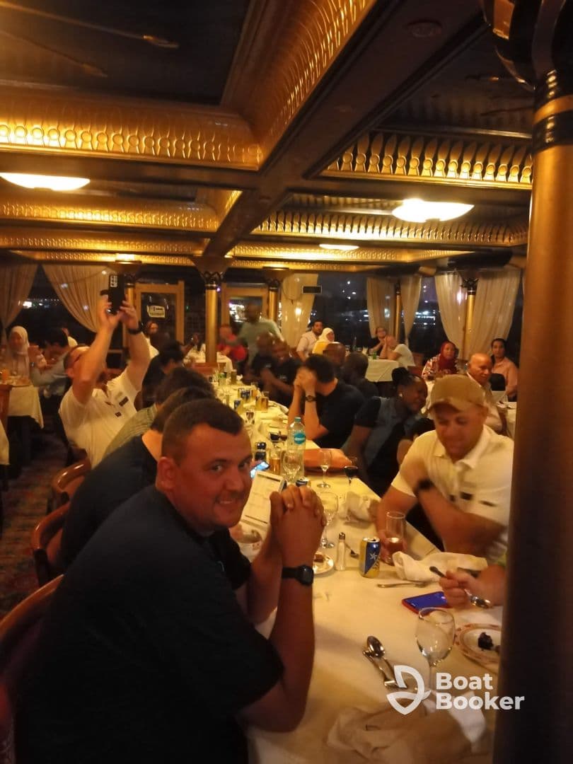 Guests enjoy a lively dining experience inside a boat restaurant, showcasing a vibrant atmosphere perfect for group gatherings.