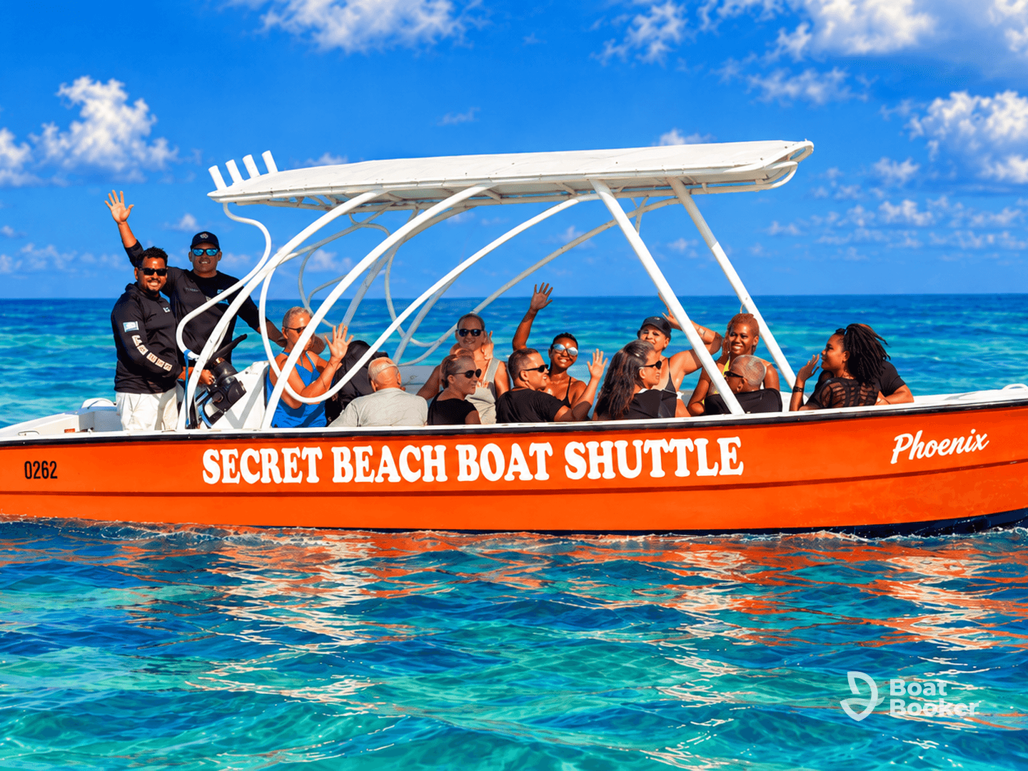 A lively group waves from the Secret Beach Boat Shuttle, enjoying a fun day on the turquoise waters — perfect for group outings and beach adventures.