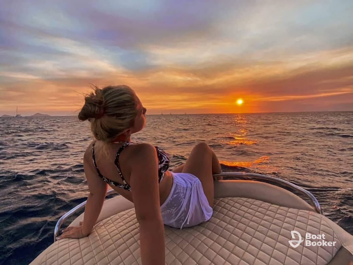 A woman enjoys a serene sunset view from the deck of a boat, capturing the perfect moment of relaxation on the water.