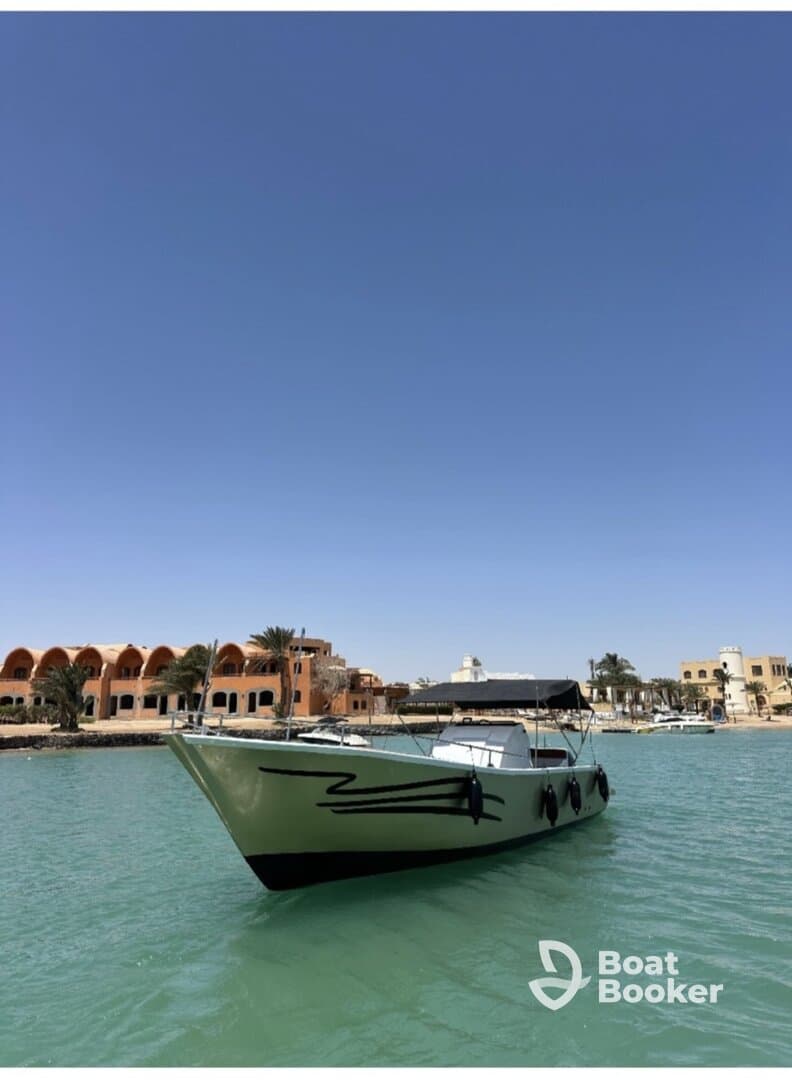 A striking view of a boat anchored in clear waters, showcasing its sleek design against a vibrant backdrop of coastal architecture.