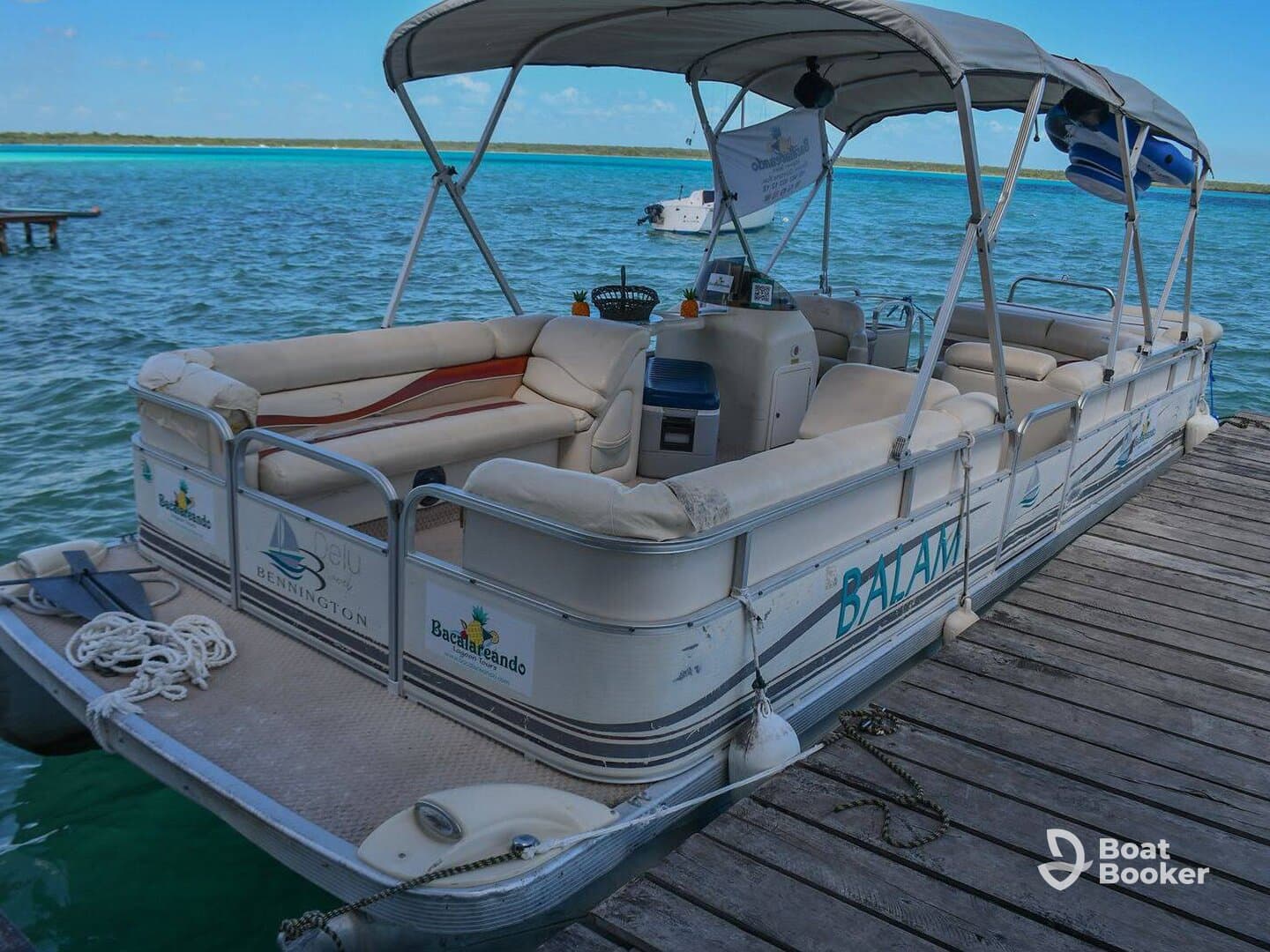 A well-equipped pontoon boat named 'Balam' docked at a serene waterfront, perfect for leisurely outings and family fun on the water.