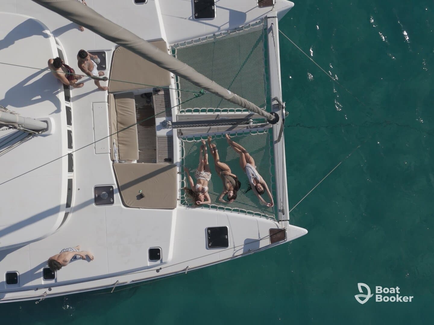 A group of friends enjoys a sunny day on a catamaran, relaxing on the nets and soaking up the sun — the perfect setting for a fun day at sea.