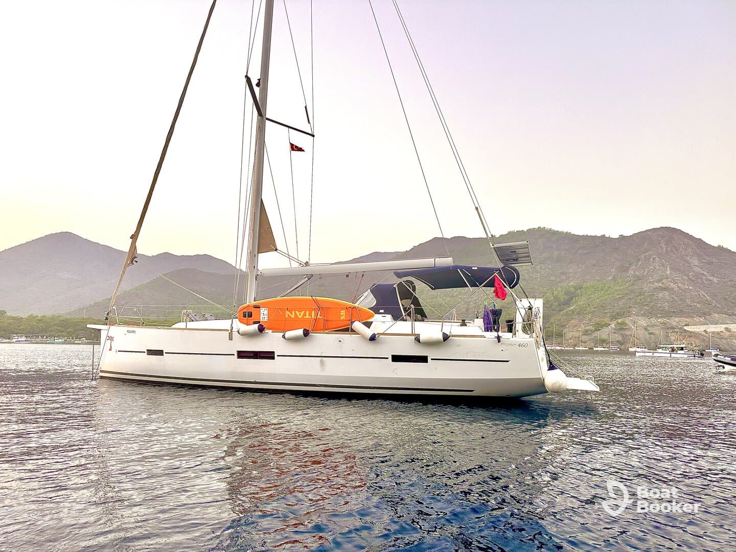 A sleek sailboat anchored in calm waters, surrounded by scenic mountains — perfect for serene sailing adventures.