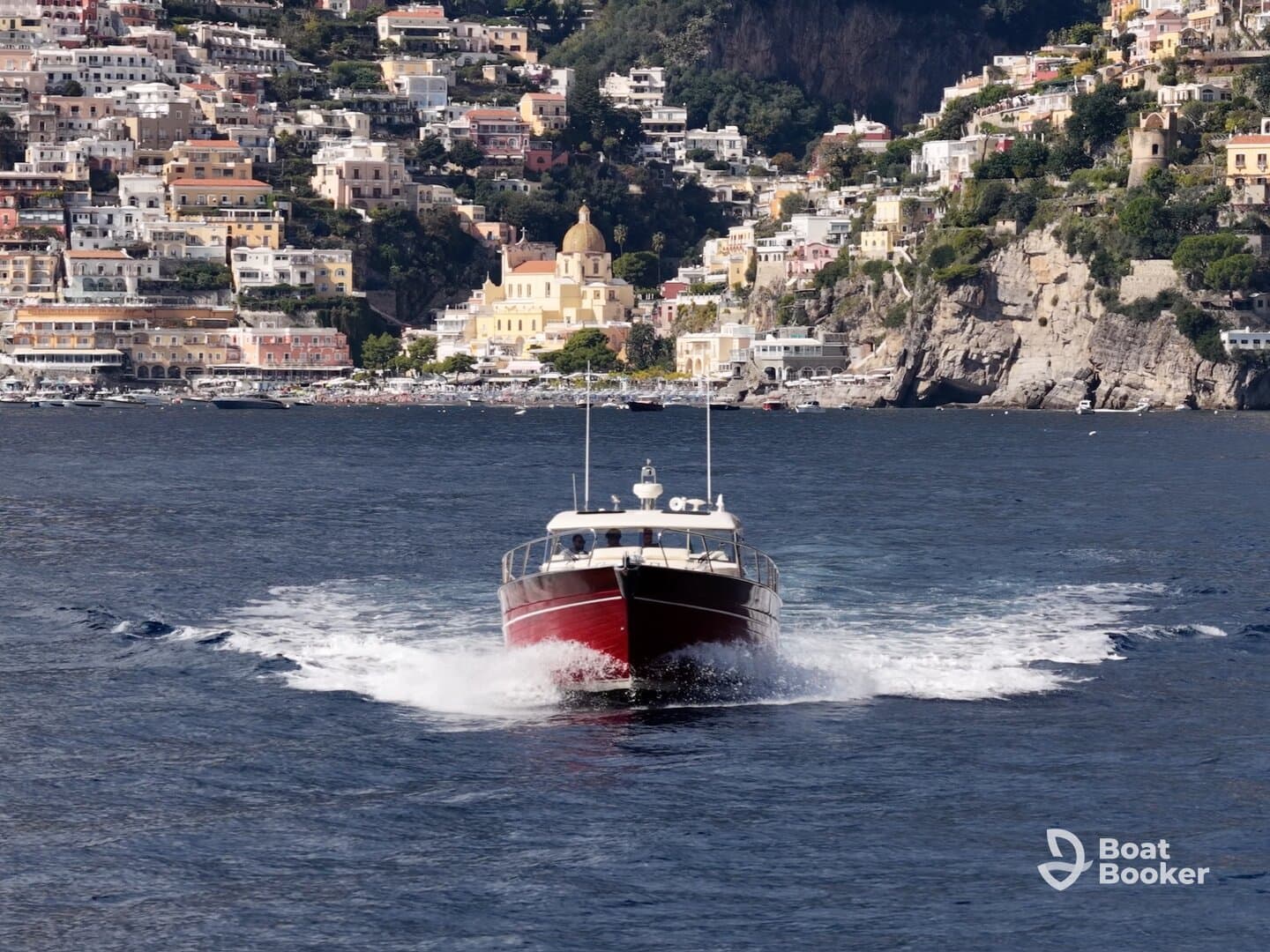 A striking speedboat navigates the waters near a picturesque coastal town, showcasing the beauty of the Amalfi Coast.