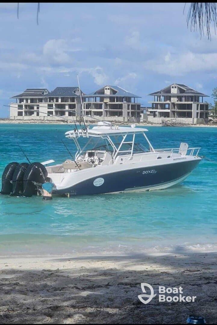 A person is seen interacting with a boat in shallow turquoise waters, highlighting a perfect day for fishing or leisure at the beach.