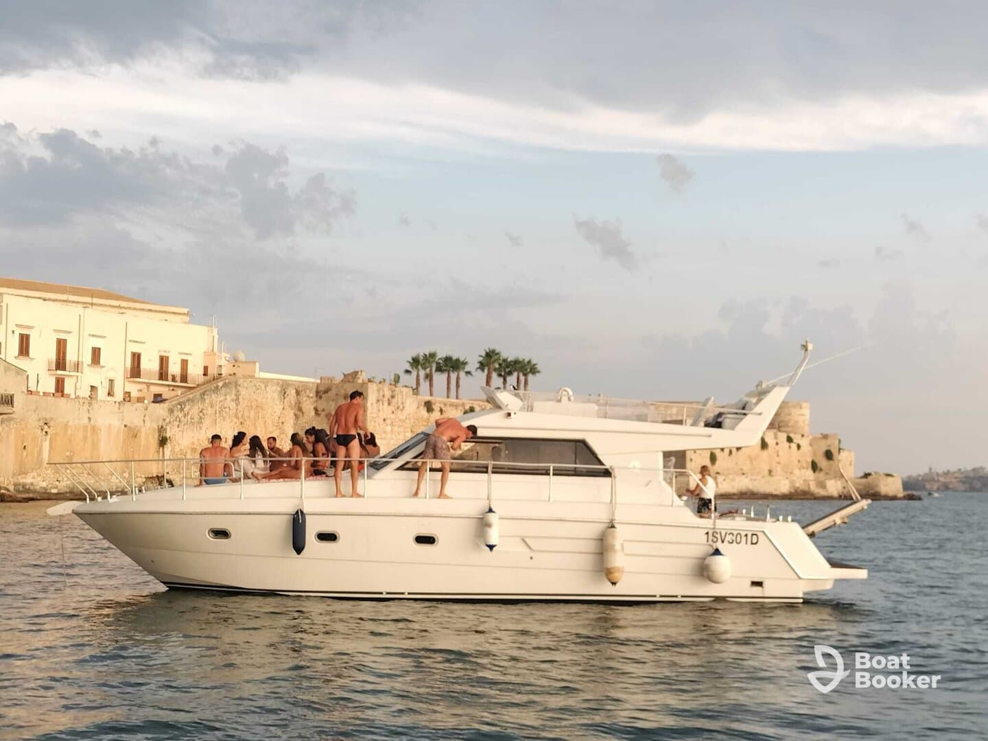 A lively group enjoys a fun day on a boat, soaking up the sun and celebrating together against a picturesque backdrop.