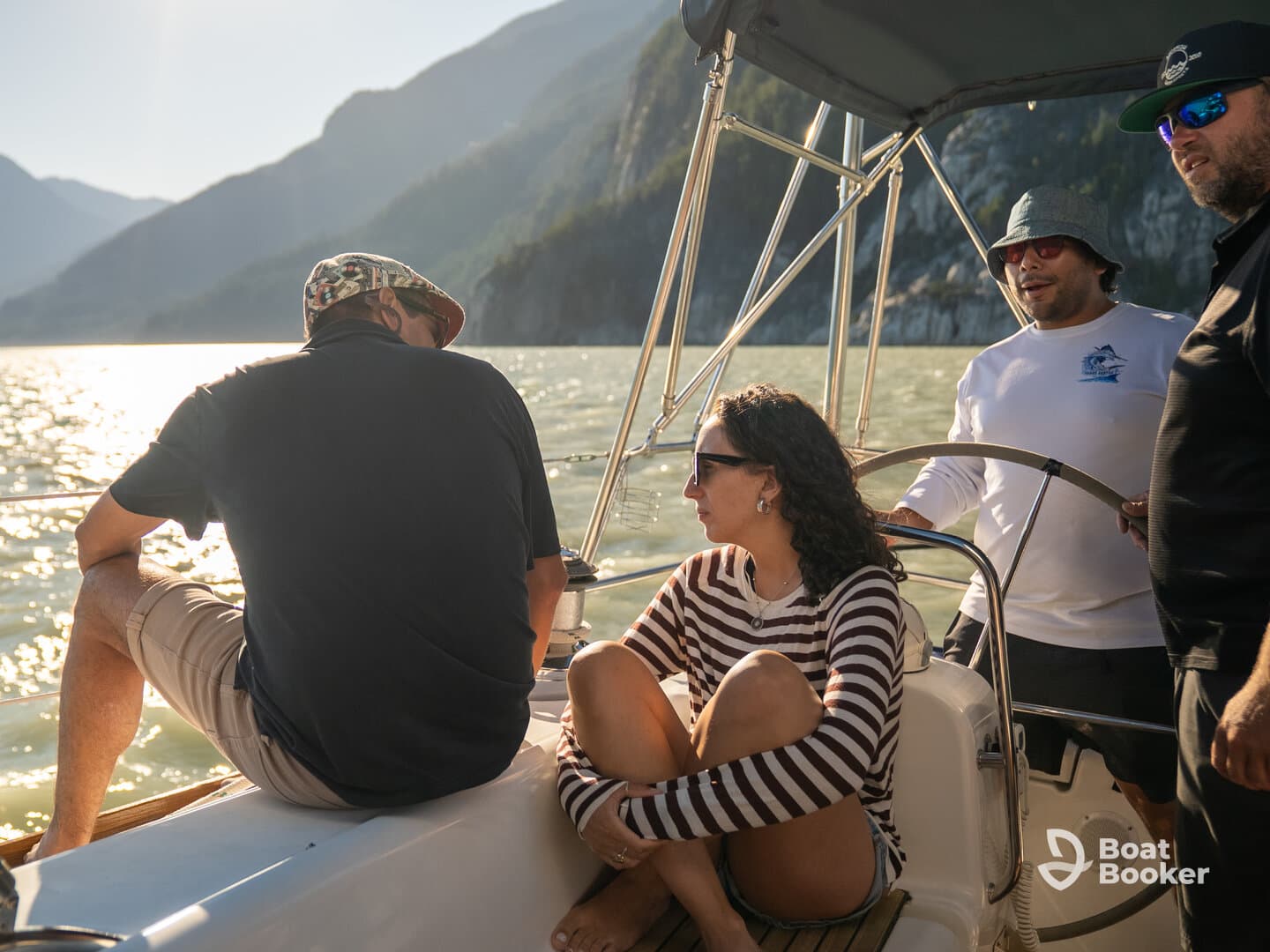 A group of friends enjoys a sunny day on a sailboat, surrounded by stunning mountain views — perfect for adventure and relaxation on the water.