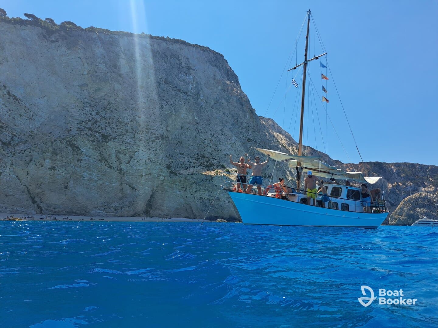 A lively group celebrates aboard a boat near stunning coastal cliffs, capturing the essence of a fun-filled day on the water.