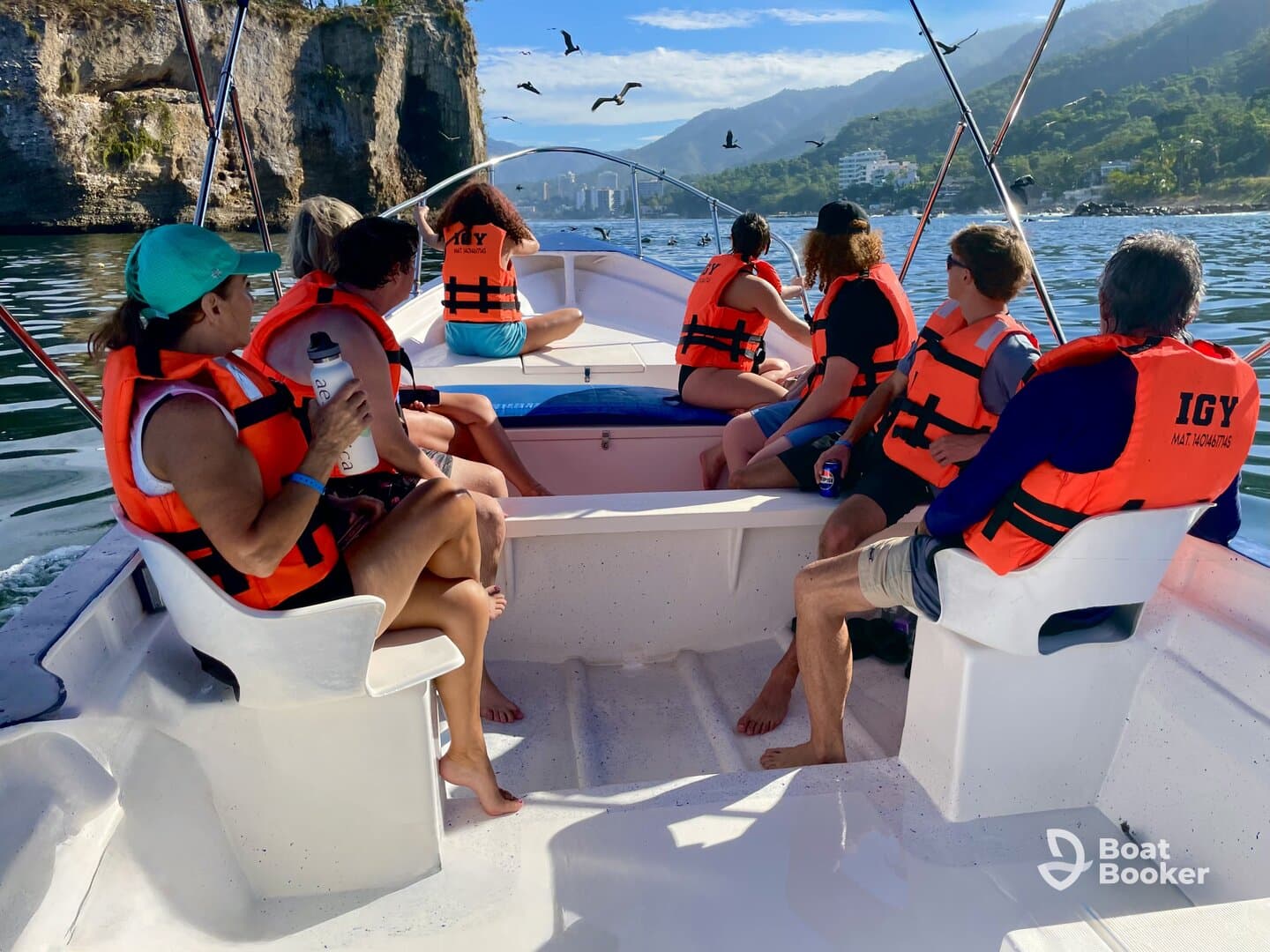 A lively group enjoys a boat ride, wearing life jackets and taking in the stunning coastal scenery — perfect for adventure seekers and nature lovers.