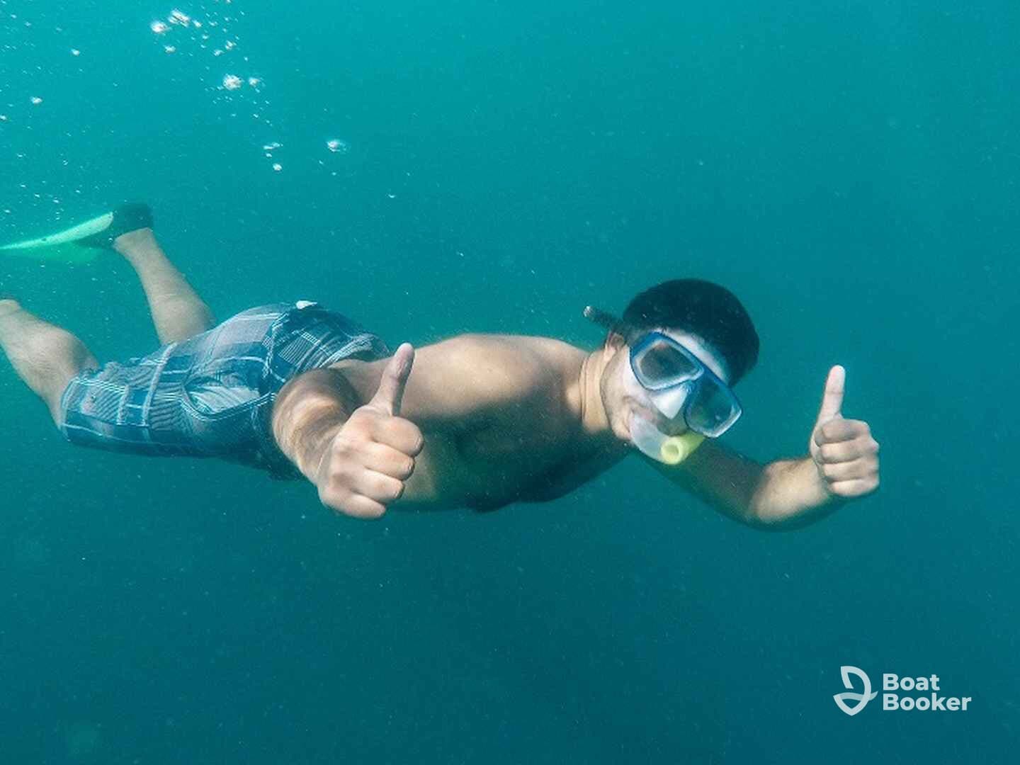 A snorkeler gives a thumbs up while exploring underwater, showcasing the excitement of marine adventures.
