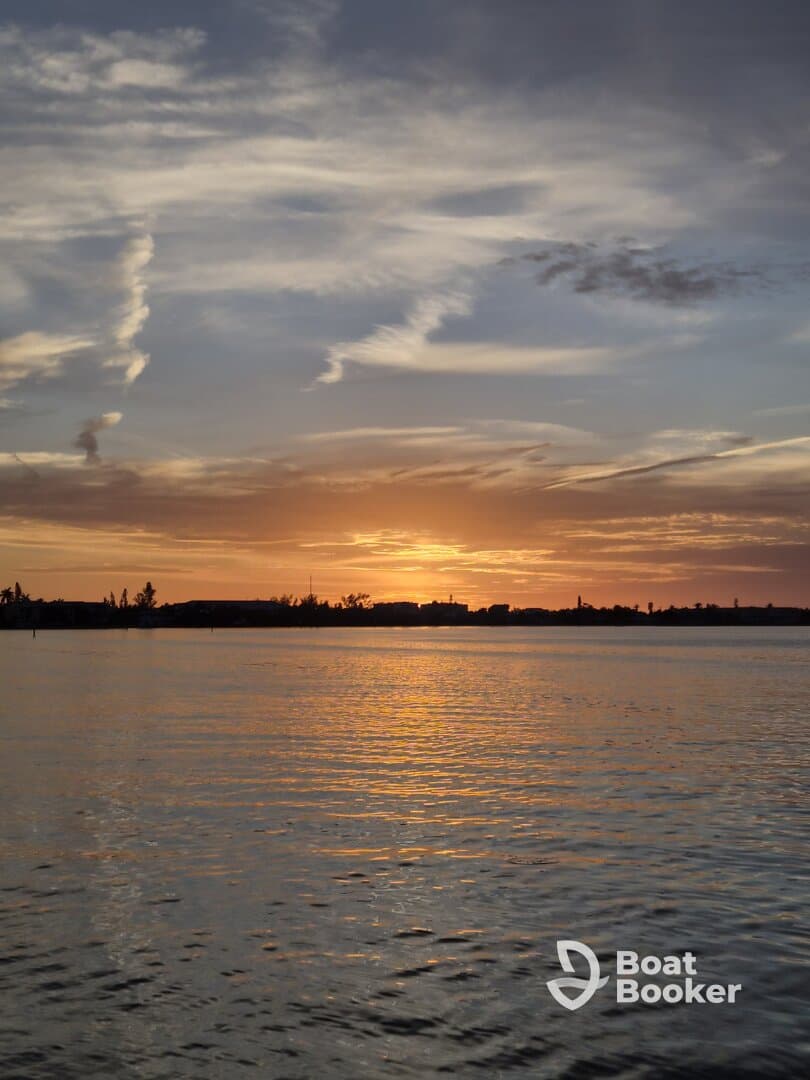 A stunning sunset over calm waters, showcasing the beautiful coastline — perfect for romantic evenings or peaceful reflections on the water.