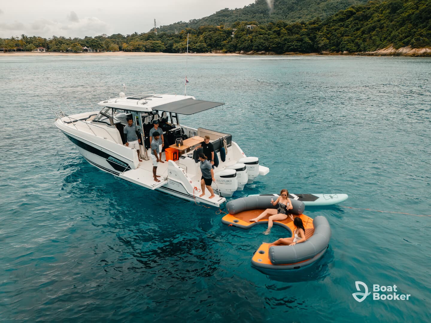 A lively group enjoys a day on the water, with some relaxing on a floating mat while others are aboard the boat, creating the perfect atmosphere for fun and adventure.
