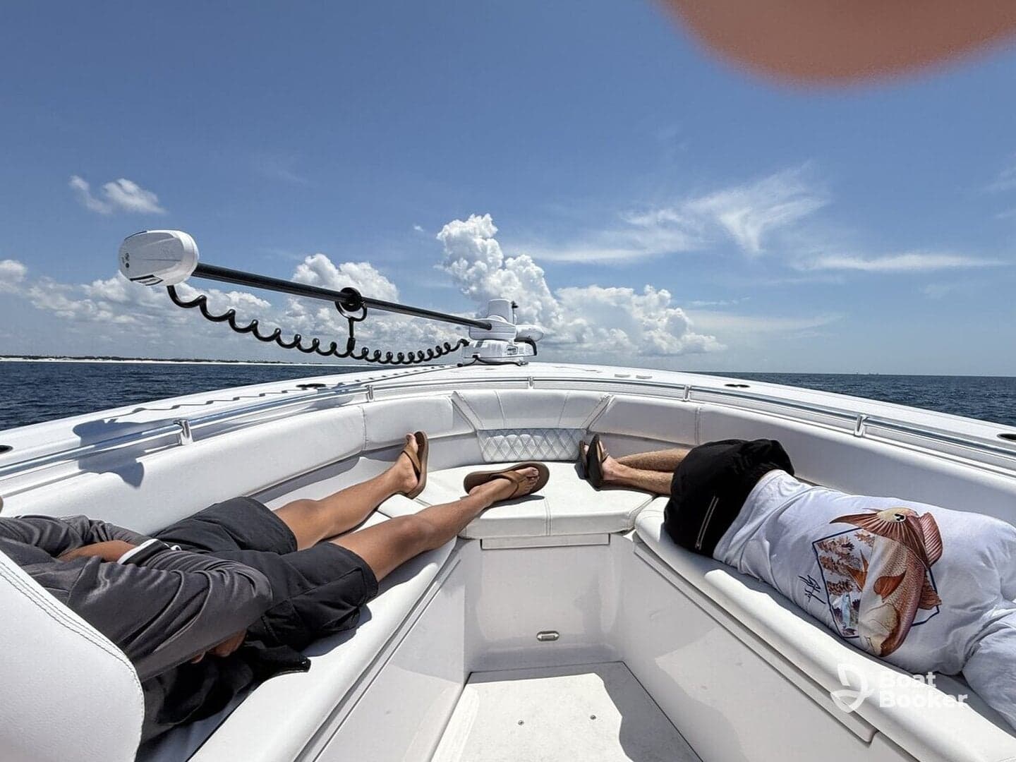 Two friends relax on the deck of a boat under a sunny sky, enjoying a perfect day on the water.