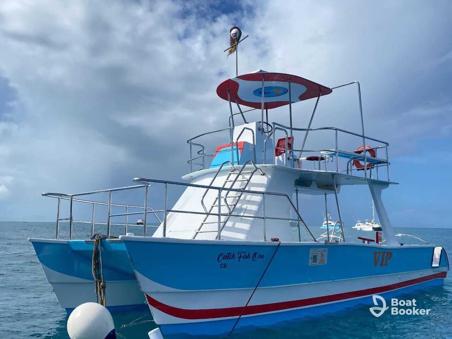 A vibrant catamaran named 'Catch Fish One' docked in calm waters, showcasing its colorful design and inviting atmosphere for fishing trips or leisure cruises.