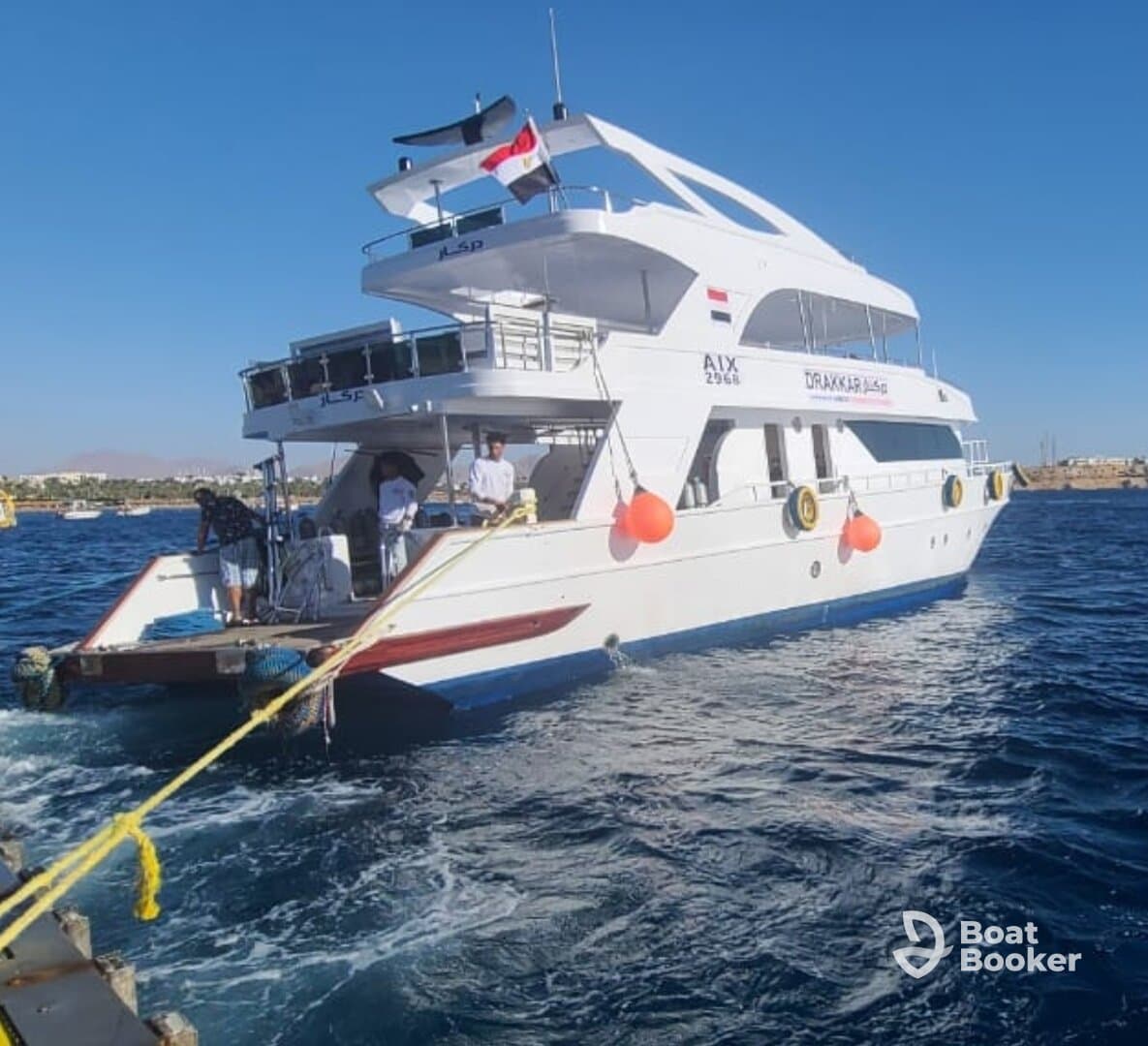 A sleek yacht is seen underway, showcasing its elegant design and vibrant colors against a clear blue sky — perfect for luxury cruising.