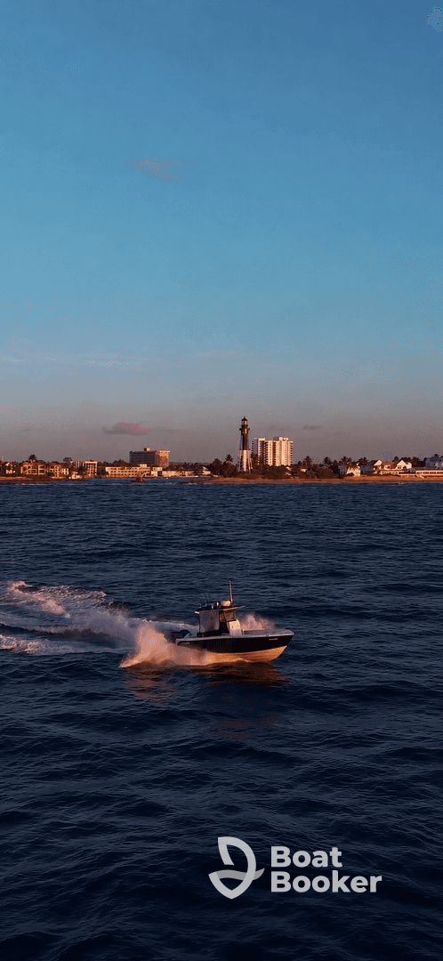 A dynamic shot of a speedboat cruising through the water, showcasing the vessel's sleek design against a scenic backdrop of a lighthouse and city skyline.