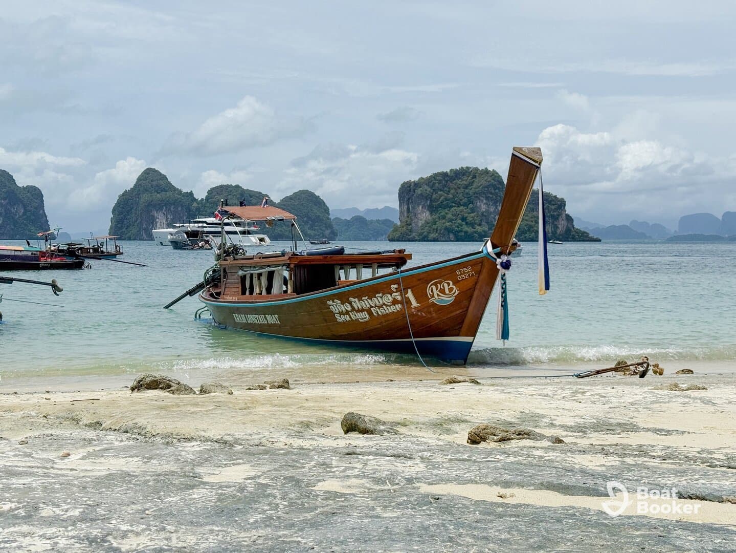 A traditional longtail boat is docked on a sandy beach, surrounded by stunning limestone cliffs and clear waters, perfect for exploring the beautiful coastline.