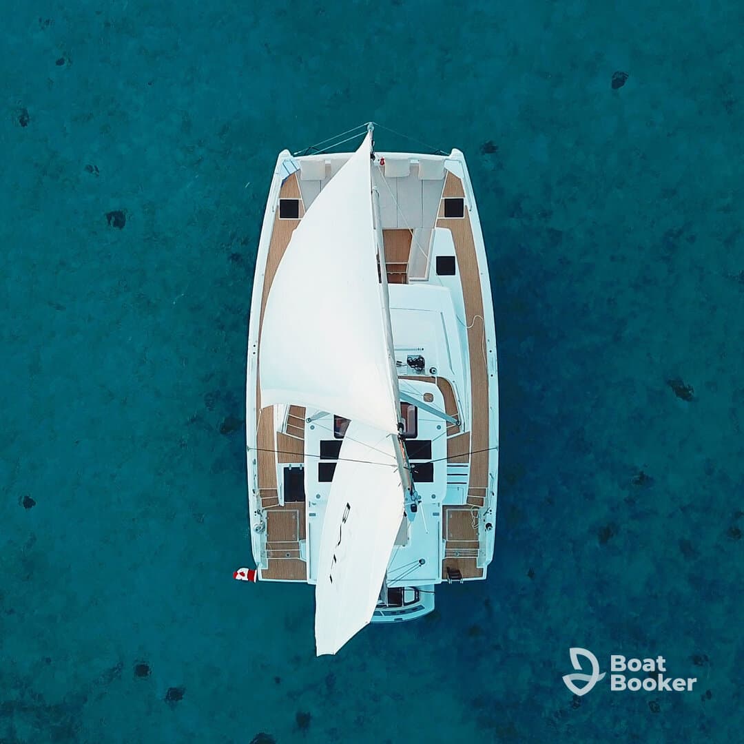 Aerial view of a sleek catamaran sailing over crystal-clear waters, showcasing its elegant design and perfect for serene ocean adventures.