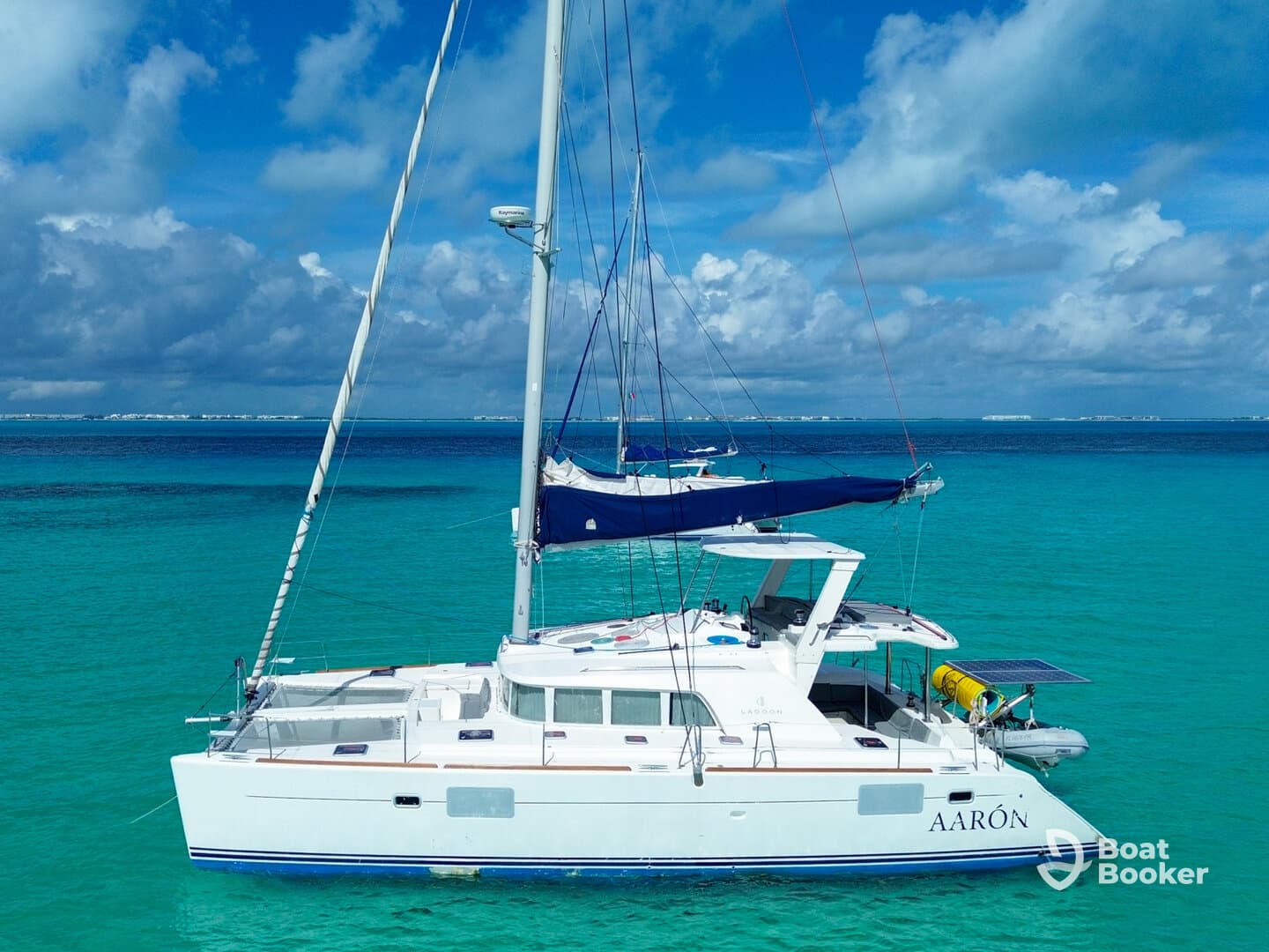 A stunning aerial view of a catamaran named AARÓN anchored in crystal-clear turquoise waters, perfect for exploring tropical destinations.