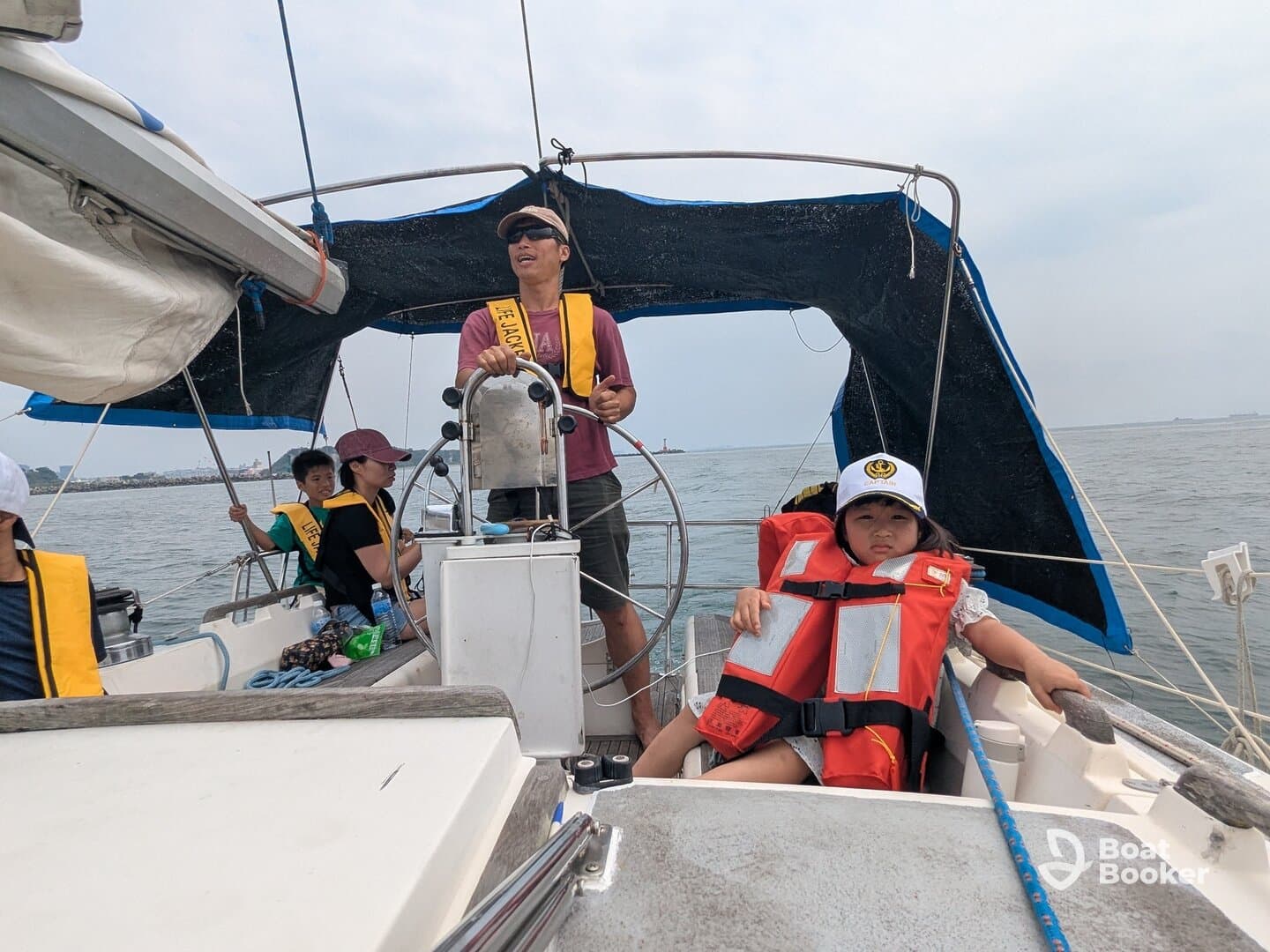 A family enjoys a sailing adventure, with children wearing life jackets while taking in the views on the boat. Perfect for family outings on the water.