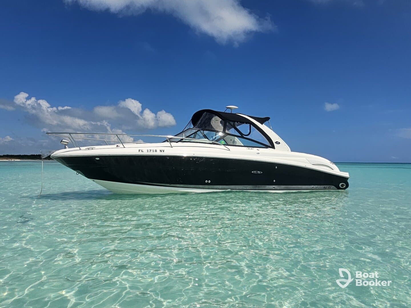 A sleek speedboat anchored in crystal-clear waters, showcasing its elegant design against a picturesque backdrop of blue skies and gentle waves.