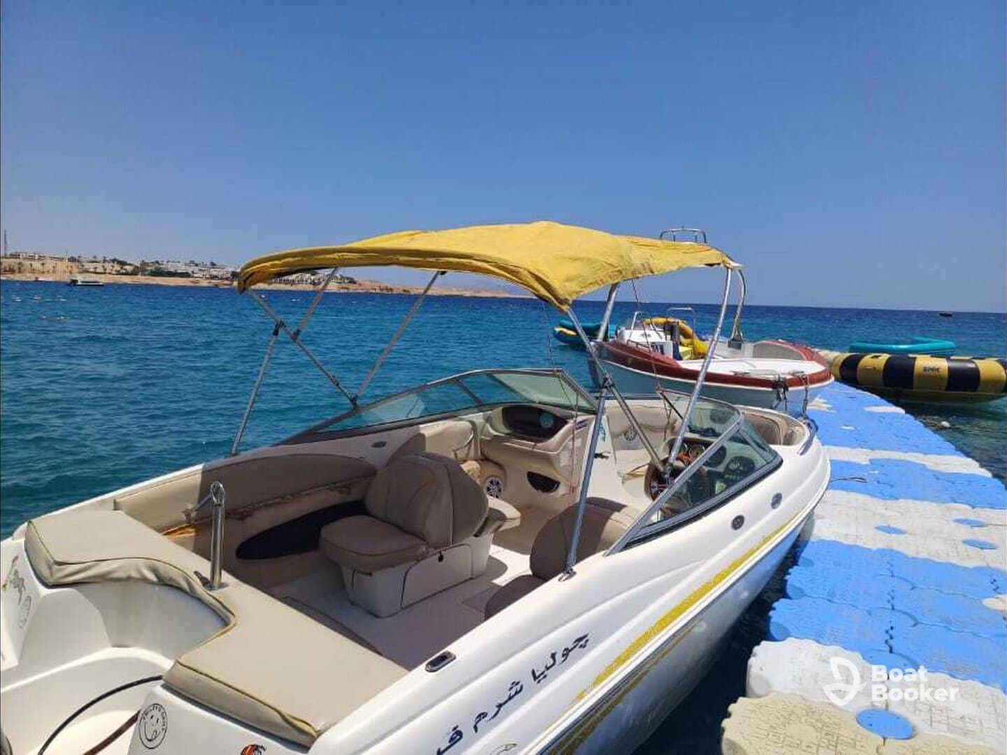 A sleek speedboat with a yellow canopy docked at a vibrant blue pier, showcasing the perfect setup for a day on the water.