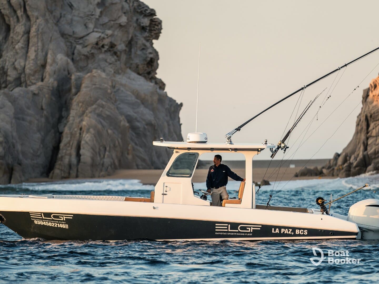 A fisherman navigates a sleek boat in the waters near Cabo San Lucas, showcasing the thrill of sport fishing in a stunning coastal setting.