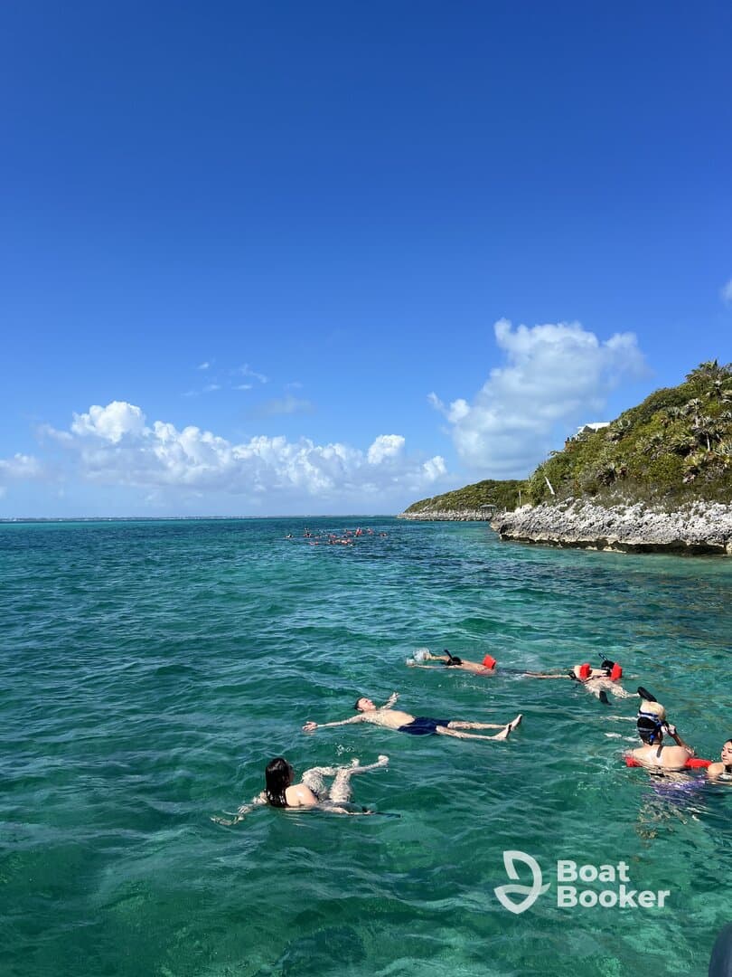 A lively group enjoys swimming in the clear waters, showcasing a perfect day for snorkeling and beach fun in a tropical paradise.