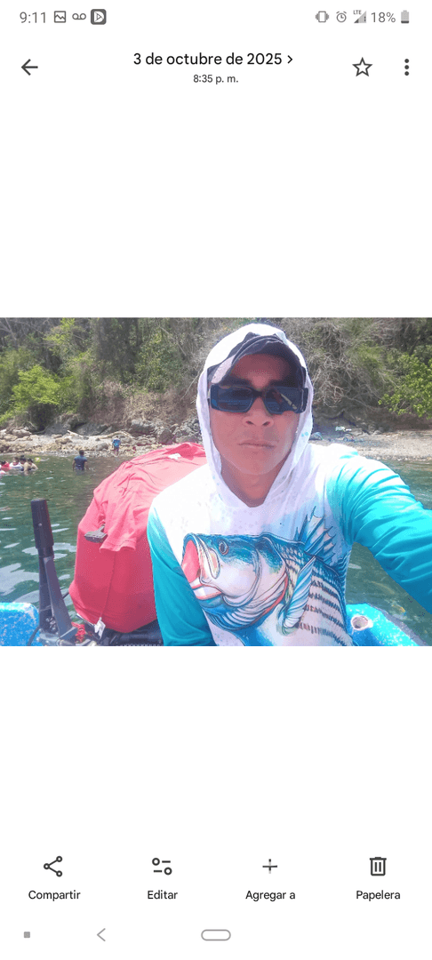 A person takes a selfie while enjoying a fishing trip on the water, surrounded by a scenic backdrop of nature.