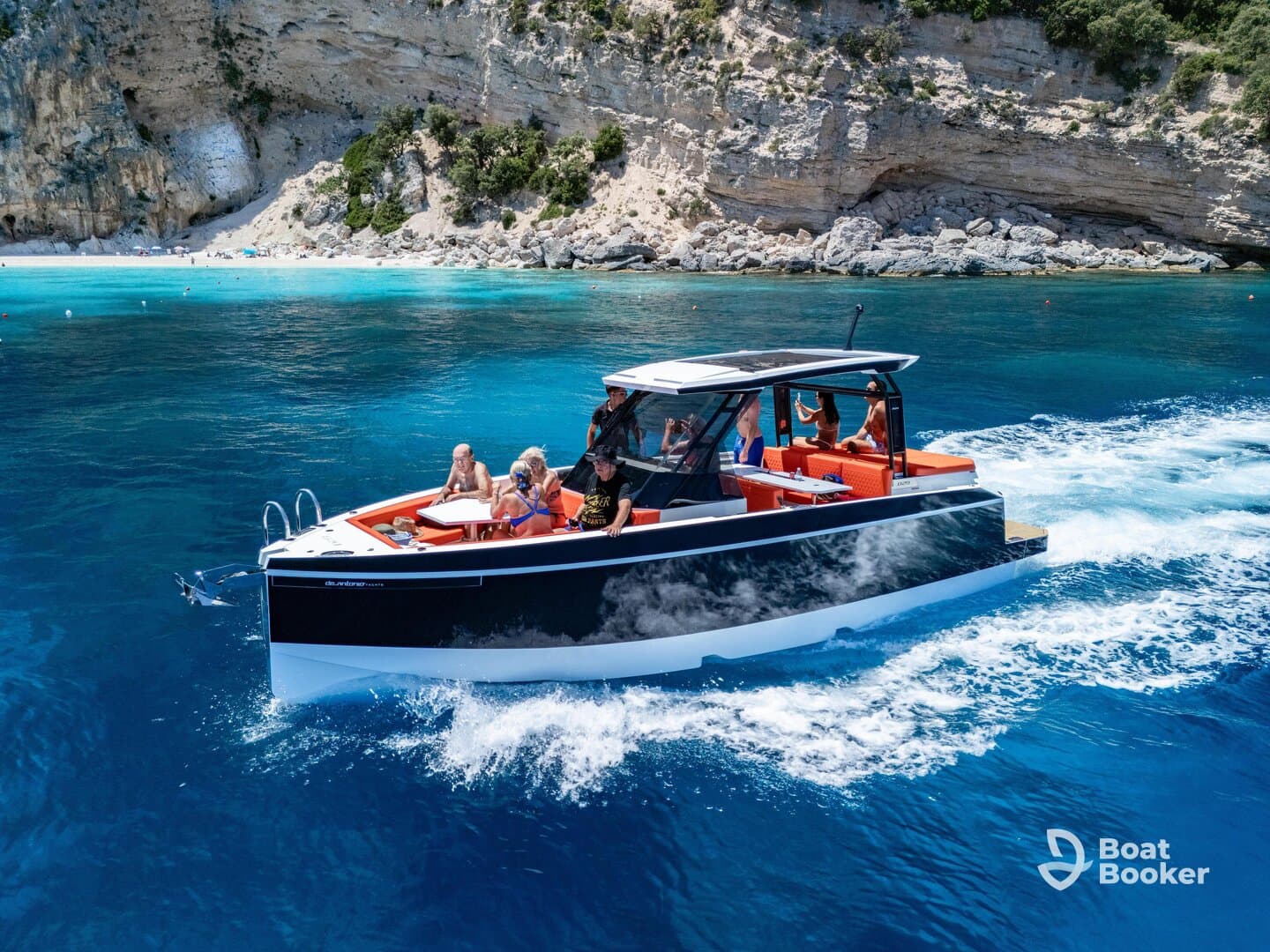 A lively group enjoys a day on the water aboard a stylish boat, surrounded by stunning turquoise waters and a beautiful beach backdrop.