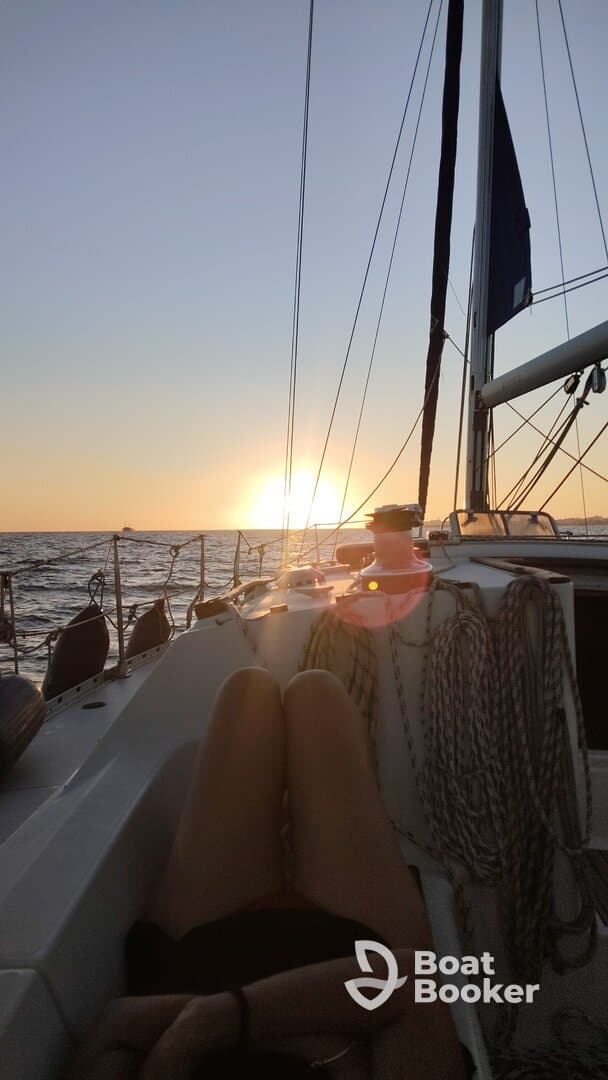 A serene sunset view from a sailboat, with a guest relaxing on the deck — an ideal moment for unwinding and enjoying the beauty of the open water.