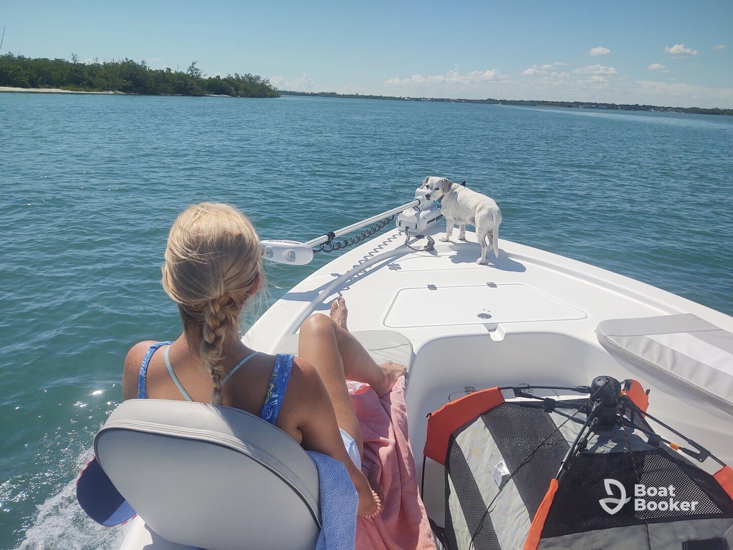 A woman relaxes on the bow of a boat with her dog, enjoying a sunny day on the water — a perfect moment for pet lovers and boating enthusiasts.