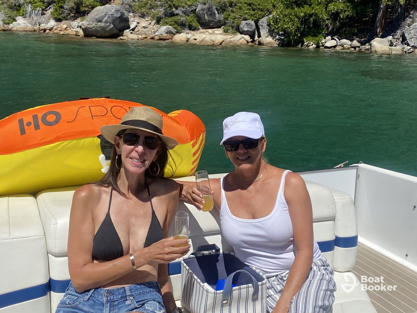 Two friends enjoy cocktails on a sunny day aboard a pontoon boat, perfect for celebrating special moments on the water.