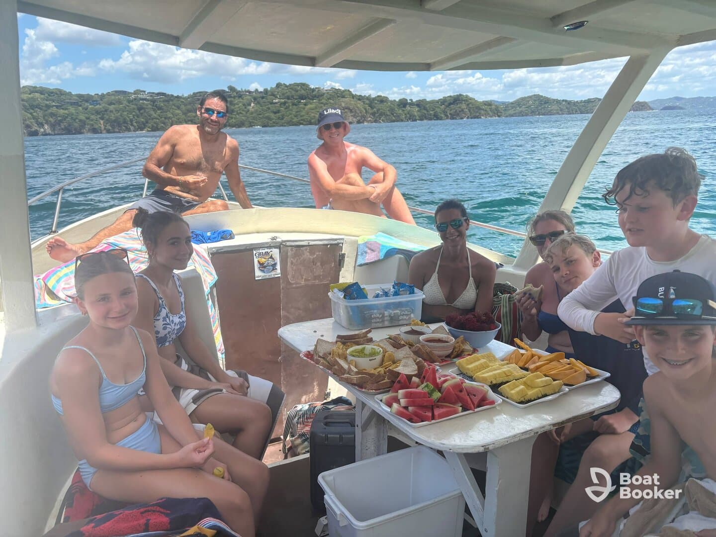 A joyful group of family and friends enjoys a delicious spread of snacks aboard a boat, capturing the essence of a fun day on the water.