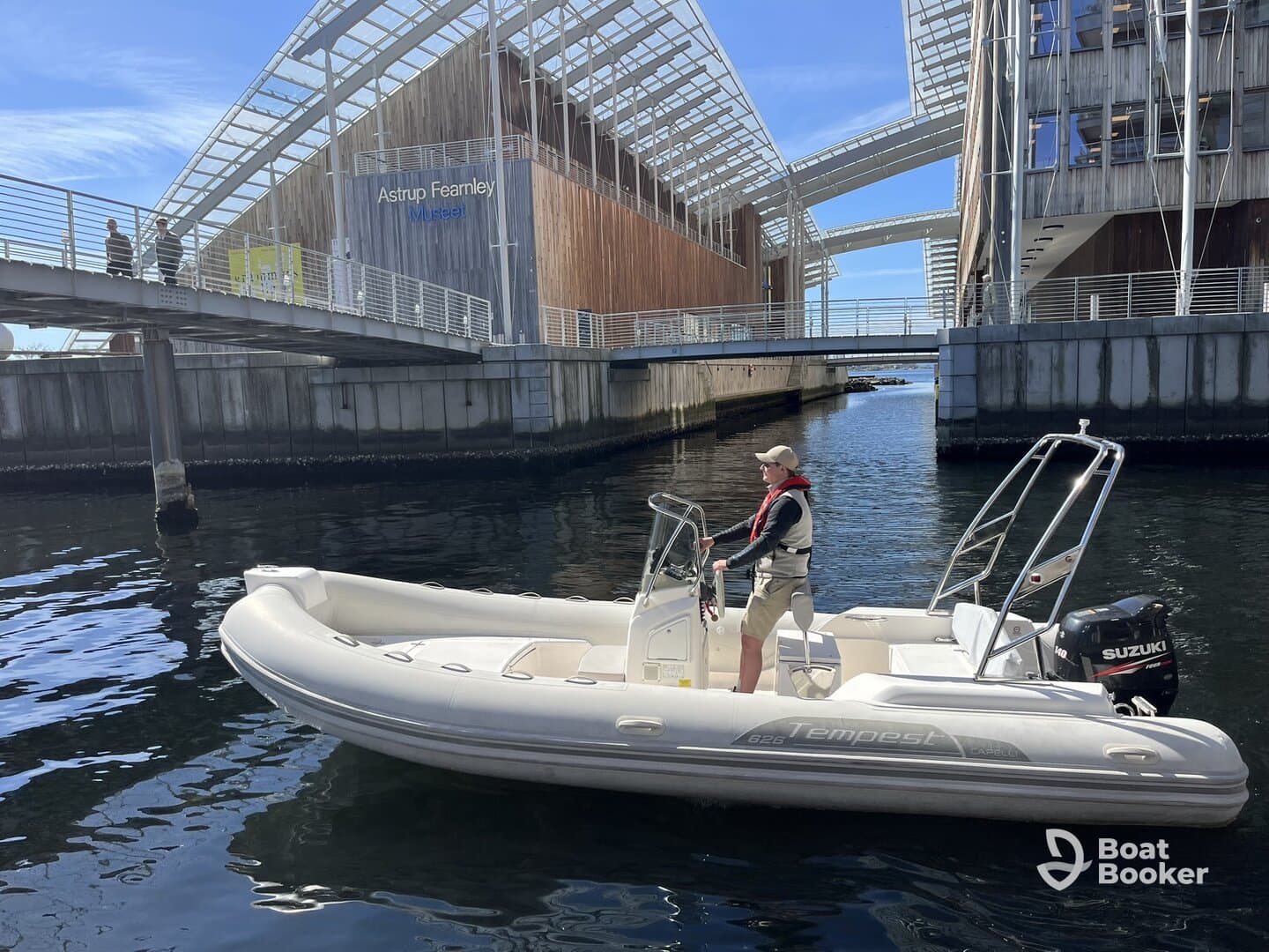 A person navigates a boat near the Astrup Fearnley Museum, showcasing a blend of urban architecture and waterway exploration.