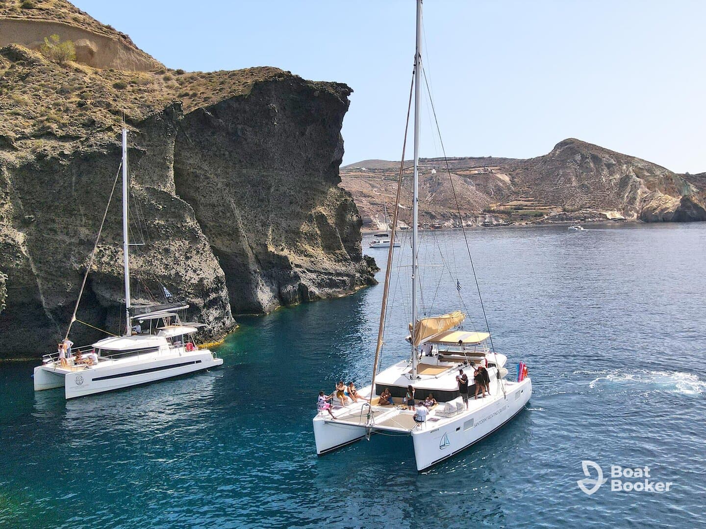 A lively group enjoys a sailing adventure on catamarans near stunning cliffs, showcasing the beauty of the coastline and the joy of on-water experiences.