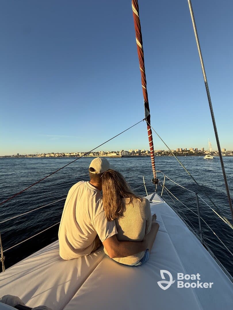 A couple enjoys a romantic moment on the deck of a yacht, overlooking a beautiful city skyline at sunset — perfect for intimate getaways.