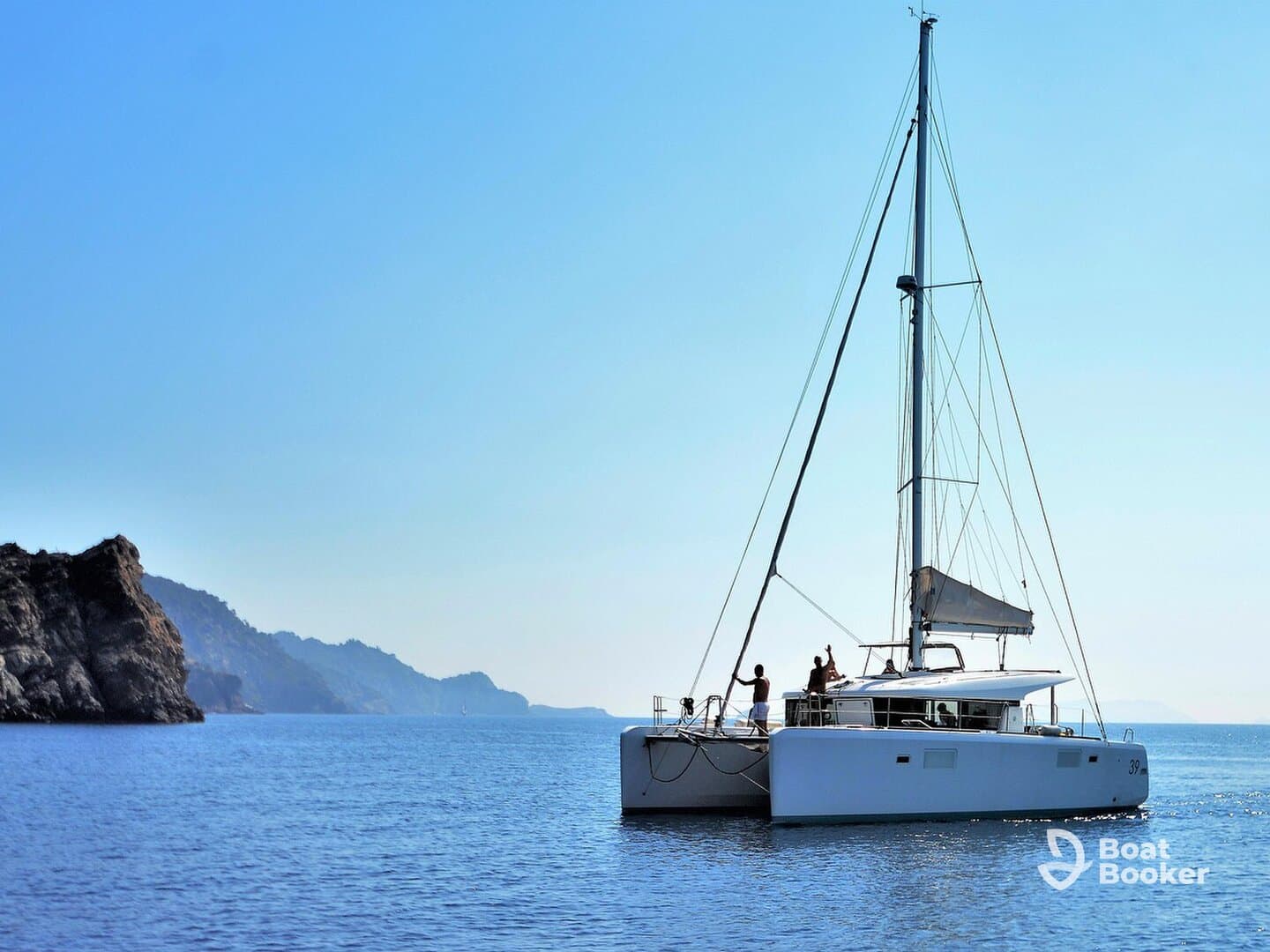A catamaran sails smoothly on calm waters with a group of people enjoying the experience, surrounded by stunning coastal scenery — perfect for adventure seekers and sailing enthusiasts.