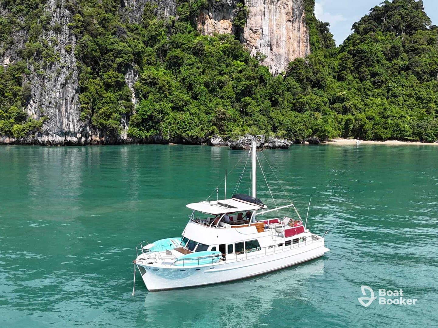 A stunning aerial view of a yacht anchored in crystal-clear waters, surrounded by lush greenery and rocky cliffs — perfect for exploring tropical destinations.